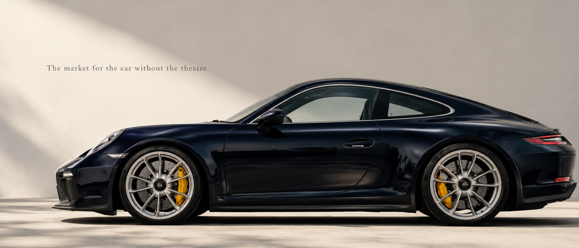 Dark navy Porsche 991.2 GT3 Touring in side profile beneath warm architectural light